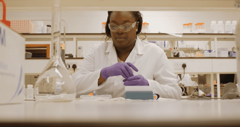 Nuffield Research Placement student working in a lab wearing a white coat and purple gloves