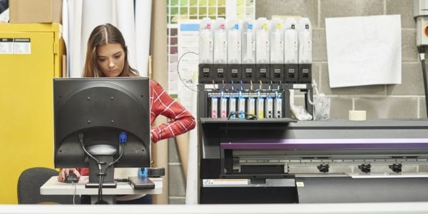 Young woman using a digital printing machine on an apprenticeship