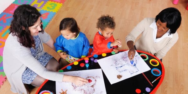 Teachers or carers doing a creative activity with two young children