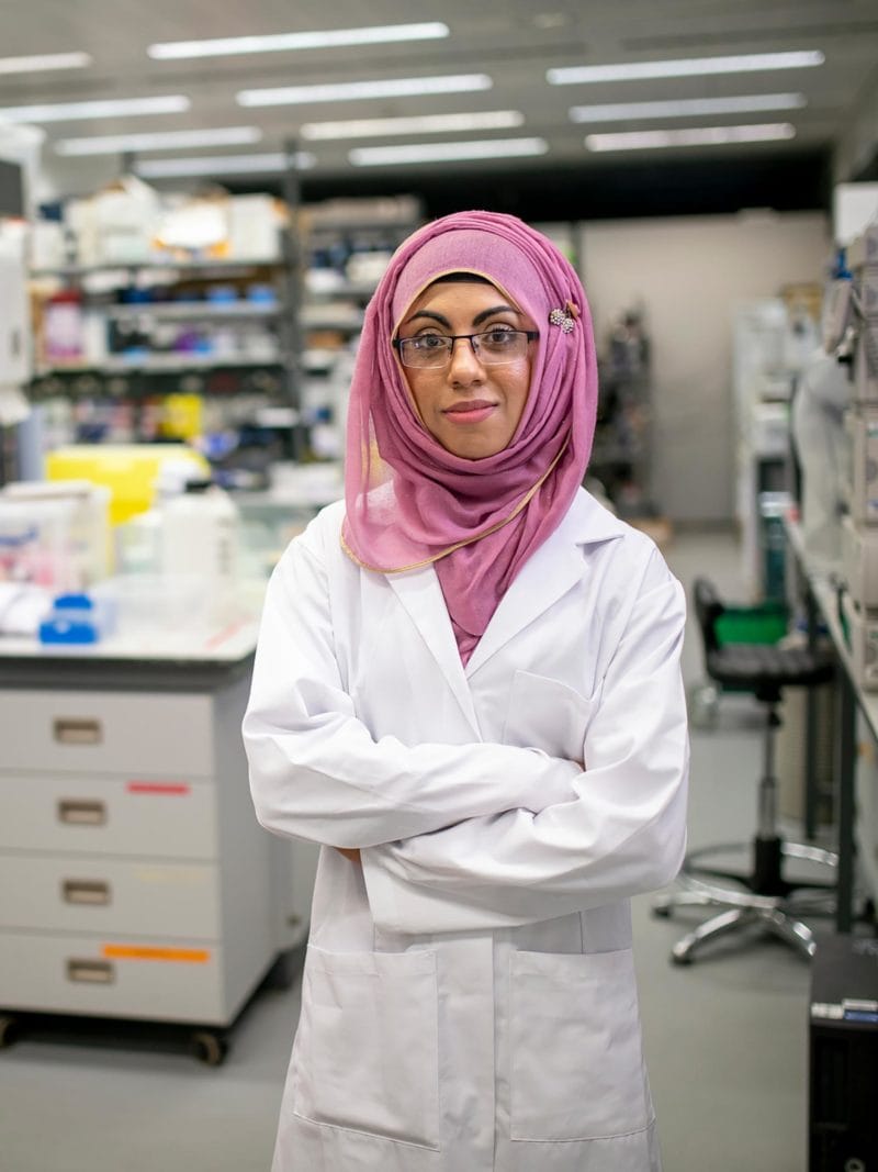 Female student in a laboratory wearing white lab coat and pink hijab