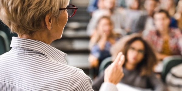 Professor leading university lecture with students blurred in background