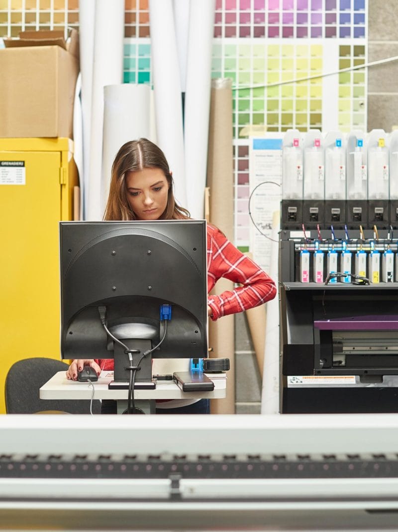 Young woman using a digital printing machine on an apprenticeship