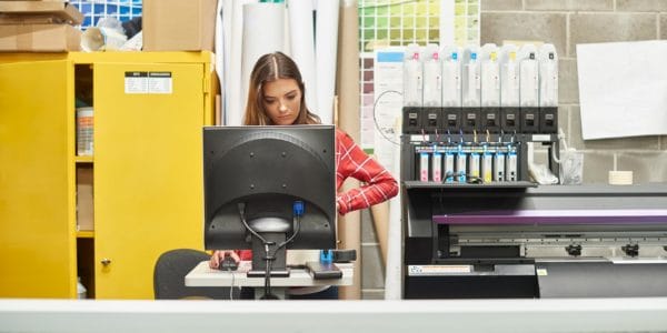 Young woman using a digital printing machine on an apprenticeship