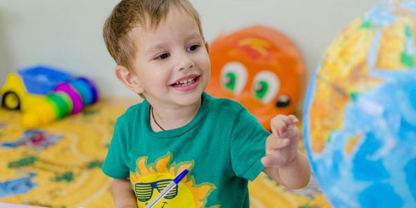Young boy draws and plays with a globe as part of nursery education