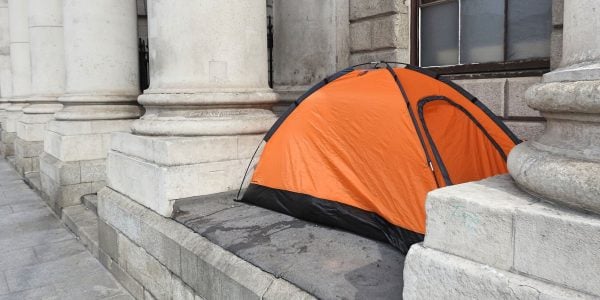 An orange tent setup between building columns in city centre