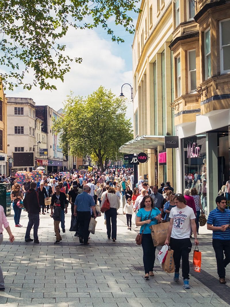 Crowded shopping street with lots of pedestrians on sunny day