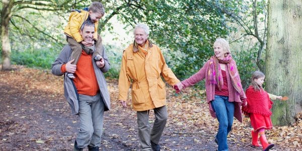 Extended family walk outdoors in the forest holding hands