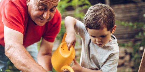 Grandfather and grandson playing in backyard with gardening tools