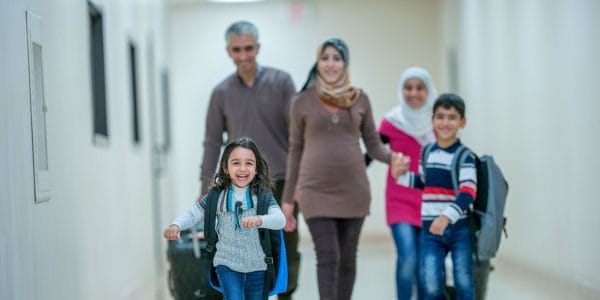 Happy Muslim family walks down corridor with luggage