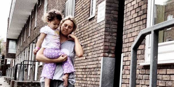 Mother carrying daughter outside their home