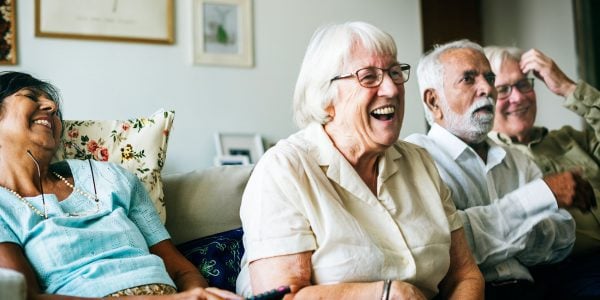 Four older people on sofa laughing