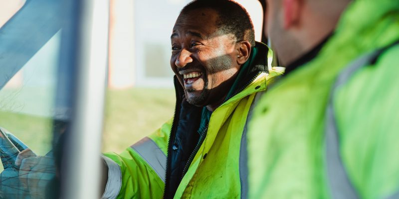 Man wearing fluorescent jacket laughing at work