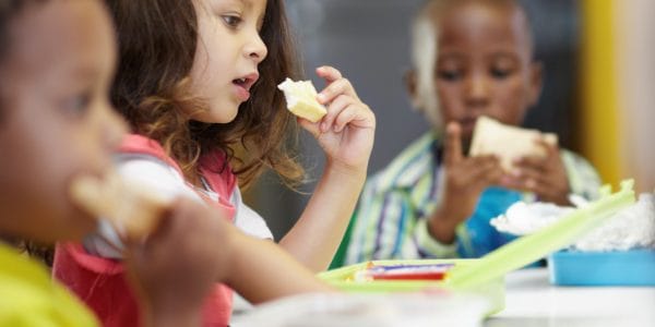 Children eat free school meals in lunch room.