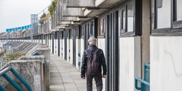 An unidentified man walking on the crescent walkway of Alexandra Road estate in London, UK