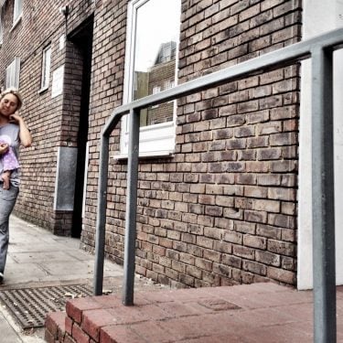 Mother carrying daughter outside their home