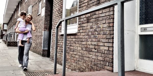 Mother carrying daughter outside their home