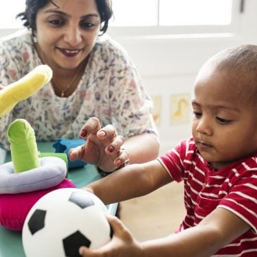 Nursery child playing with teacher in the classroom