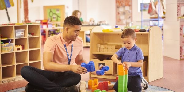 Teaching assistant plays with little boy at nursery