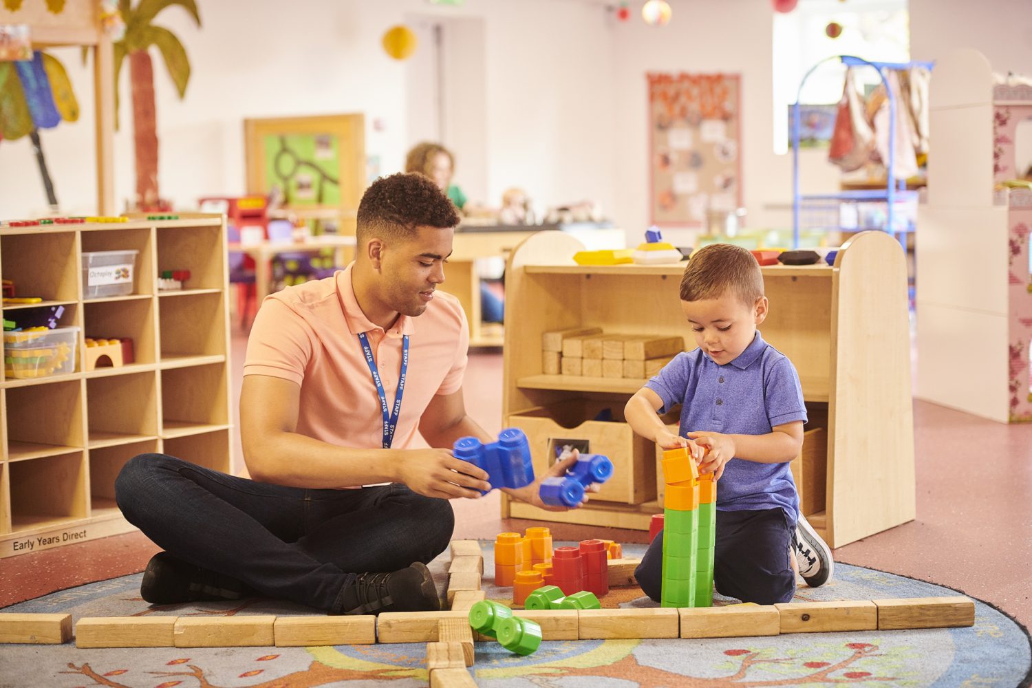 Teaching assistant plays with little boy at nursery
