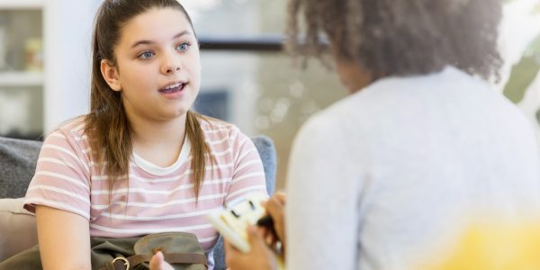 Serious-teenage-girl-gestures-as-sits-on-couch-in-school-counselor-office-Mental-health-service-provision-for-children-state-care-England-PROJ