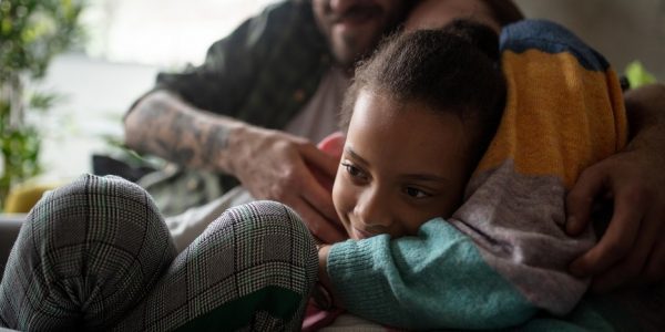 Mother and father hug daughter on sofa