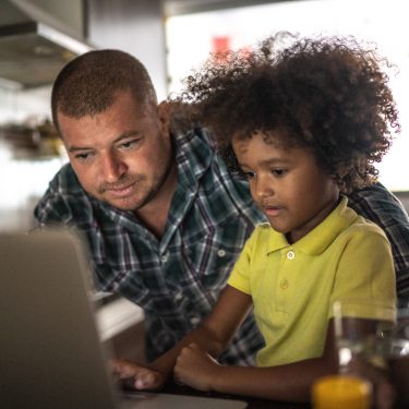Father and son using laptop at home