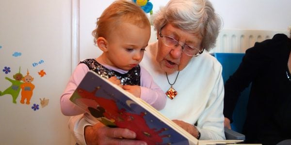 Grandmother reads large picture book to infant granddaughter