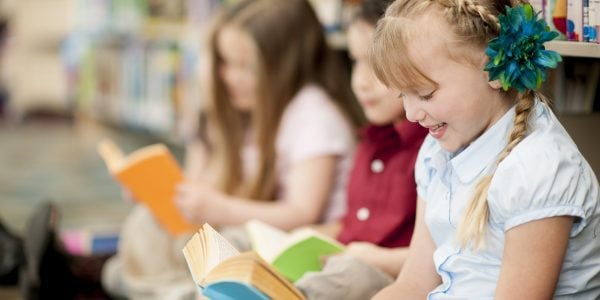 Young students practicing reading in the library at school.