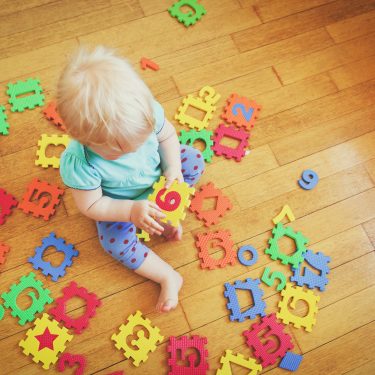Pre-school child playing with game to improve early numerical skills
