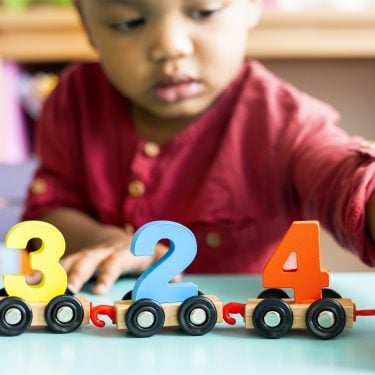 Little boy playing mathematics wooden toy at nursery