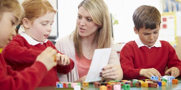 Primary School Pupils And Teacher Working With Coloured Blocks