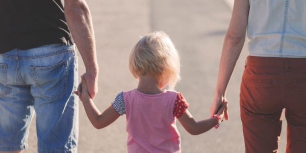 Child holds hands with parents