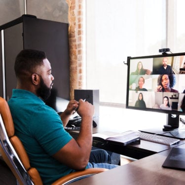 The future of work and wellbeing. A man working from home during the COVID-19 crisis, having a video meeting with colleagues