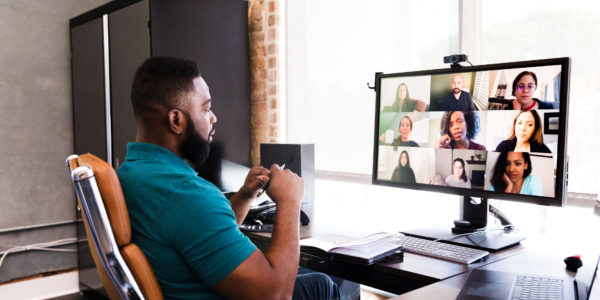 The future of work and wellbeing. A man working from home during the COVID-19 crisis, having a video meeting with colleagues