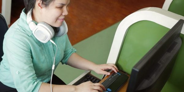 Young woman with a visual impairment working on a computer with a braille display