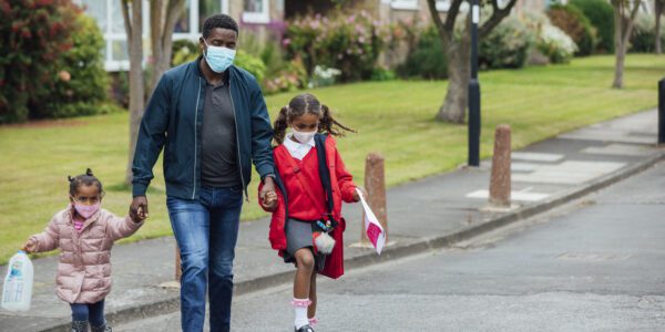 COVID-19 and the impact of school closure: a father walking his daughters home from primary school, wearing masks