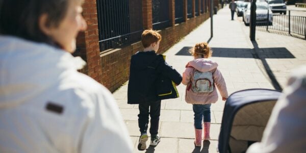 Two children walk ahead of two adults, one pushing a pram