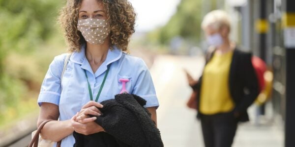 Nearly half of adults have experienced discrimination during Covid-19 pandemic: a nurse wearing a face mask waiting for a train