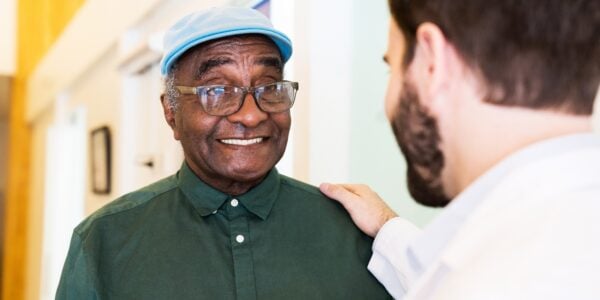 New report reveals the extent of the barriers migrants face accessing healthcare during the pandemic: an older man talking to a healthcare practitioner