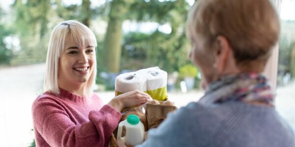 A young woman brings shopping to an older neighbour who is self isolating: Neighbourly relations better now than before the pandemic