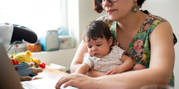 A woman holds her baby while working from home