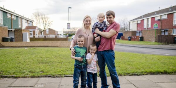 Family with three children standing in front of houses: Understanding tenancy sustainment in social housing