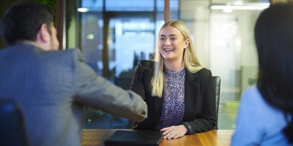 A young woman at a job interview shaking hands with the interviewer