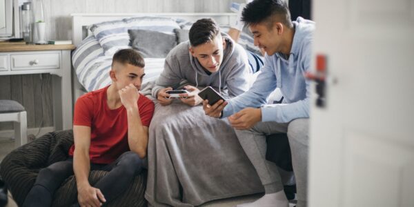 Three teenage boys looking at a smartphone together at home: Full Fact Report 2022: Tackling online misinformation in an open society