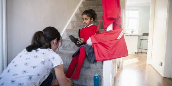 A woman helping a little girl get ready for school