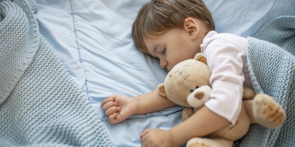 Toddler asleep holding a teddy bear