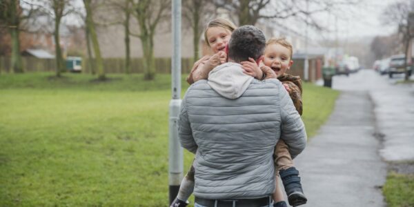 A father carries two young children