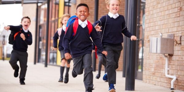 A group of primary school children looking happy as they run out into the playground