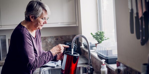 Older woman fills up the kettle at home