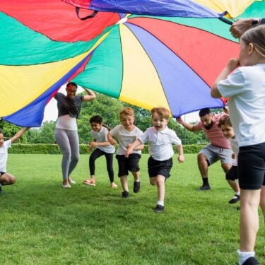 Reception class children using a parachute in a PE lesson